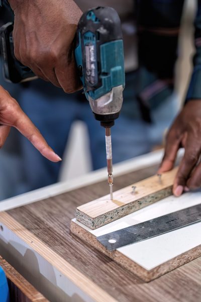 In wooden industrial senior carpenter teach trainee engineer use power tool drilling screw to wood