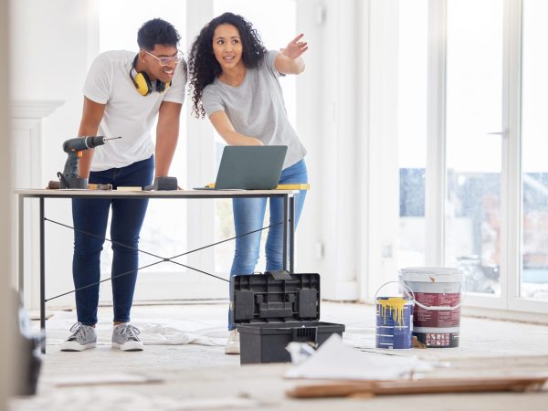 Shot of a young couple using a laptop while busy renovating a house.