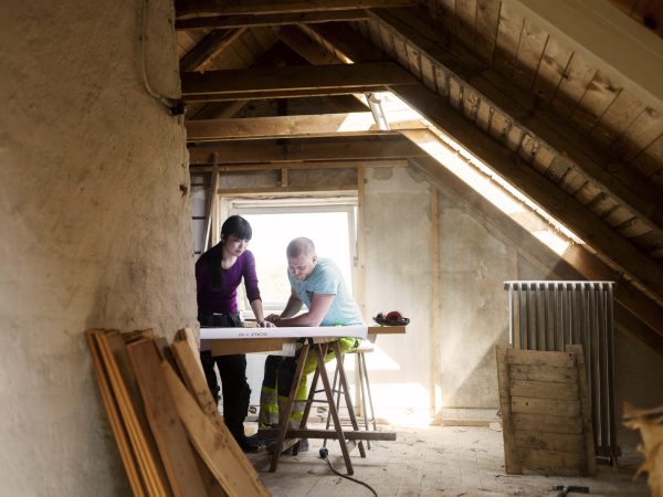 Two people collaborating on a DIY home renovation project in a bright attic space.